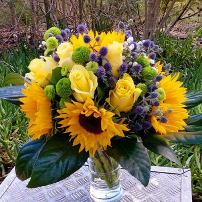 Sun Blooming - A splendid vase arrangement created using sunflowers, yellow roses, thistle with complimentary foliage. Hand delivered with care in and around Cape Town by Shirleys Flower Designs.